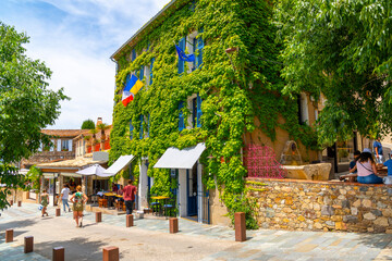 Wall Mural - Ivy and plants cover the facade of medieval shops and cafes in the historic old town of Grimaud, France, in the Provence Cote d'Azur region.