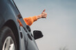 Unrecognizable woman hand sticking out the car window holding thumbs up 
