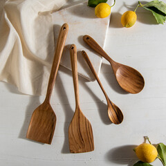 wooden kitchen tools with lemons on white marble