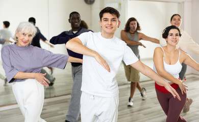 Wall Mural - Caucasian man rehearsing modern dance with group in dance school