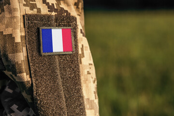 Wall Mural - Close up millitary woman or man shoulder arm sleeve with France flag patch. France troops army, soldier camouflage uniform. Armed Forces, empty copy space for text
