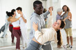 © JackF - Smiling African American man supporting young girl, dancing slow foxtrot in pair in modern choreography studio
