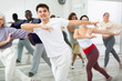 © JackF - Group of active people engaged in a dance studio practicing energetic swing during lesson