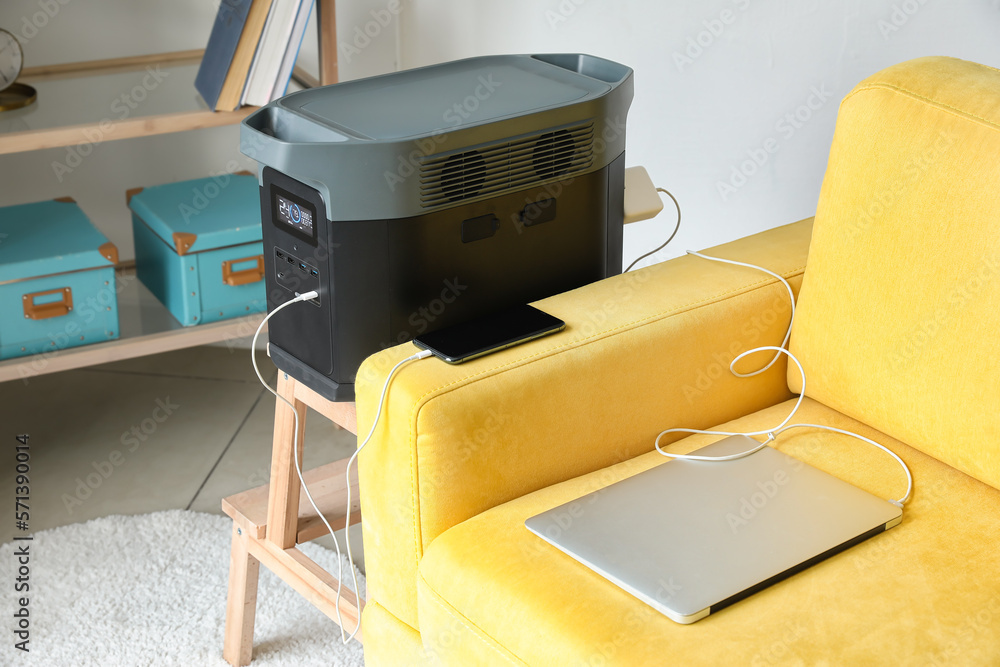 Portable power station charging gadgets on stool in living room
