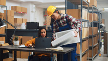 Female Wheelchair User Checking Logistics On Laptop In Warehouse Space, Working With Employee To Send Products Packages. Person With Physical Disability Doing Quality Control, Small Business.