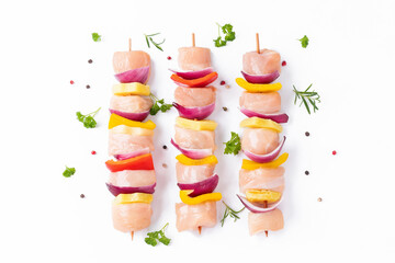 Wall Mural - Raw pieces of chicken skewers with pepper onion and pineapple on a white background.Uncooked mixed meat skewer with peppers.Skewers with pieces of raw meat, red, yellow and green pepper.Top view.