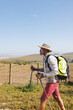 © Wavebreak Media - Side view of african american senior man wearing hat with backpack and poles hiking on land