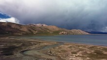 This Breathtaking Drone Footage Gives A Unique Perspective Of Chatyr Kol Kyrgyzstan's Stunning Landscape During A Summer Storm. Wild Horses Near The Lake Surrounded By Majestic Mountains