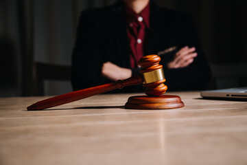 Justice and law concept.Male judge in a courtroom with the gavel, working with, computer and docking keyboard, eyeglasses, on table in morning light