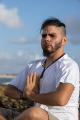 young man on the beach doing yoga