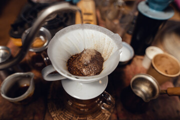 Wall Mural - Man pouring hot water on ground coffee with paper filter to making a drip coffee