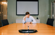 © Cavan Images - Man sat in a meeting room with his head in his hands looking stressed