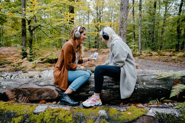 Two Women streaming a Video on a Smartphone in a remote forest
