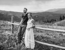 Black And White Of Bride And Groom Leaning Against Fence In Wyoming