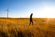 © Cavan Images - Female operator walks through a wind farm at sunset