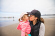 © Cavan Images - Mother gives daughter big kiss while at the beach.