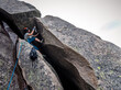 © Cavan Images - Man rock climbing rock wall while hauling backpack