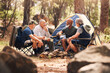 © Azee J/peopleimages.com - Senior people, camping and relaxing in nature for travel, adventure or summer vacation together on chairs by tent in forest. Group of elderly men talking, enjoying camp out conversation in the woods
