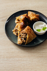 Wall Mural - Crepes stuffed with chicken and mushrooms with sour cream on the wooden table.