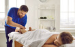 © Studio Romantic - Male therapist work with female client lying on table in wellness salon or spa. Masseur or physiotherapist do manual massage patient leg relive strain or spasm in muscles. Relaxation and recovery.