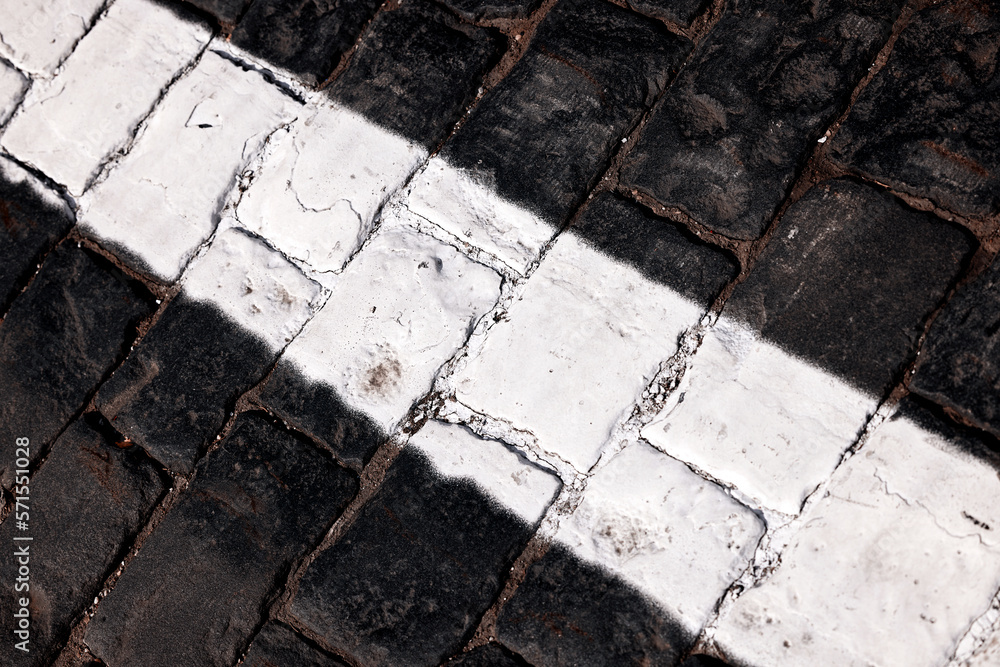 Road markings on the paving stones. The old road in the city. Historic city center with preserved cobblestones. Line markings on a stone road