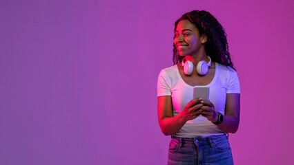 smiling black female holding smartphone and looking aside at copy space