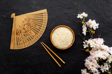 Wall Mural - Asian table setting - rice bowl with cherry branch and fan. Top view