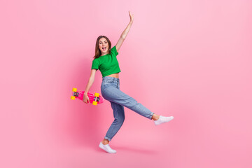 Wall Mural - Full length photo of excited sweet girl wear green crop top riding skate walking empty space isolated pink color background