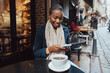 © fotofabrika - Young african woman using smart phone in a modern cafe