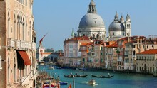 Grand Canal In Venice With Gondolas Crossing The Water And Cathedral Santa Maria Della Salute.