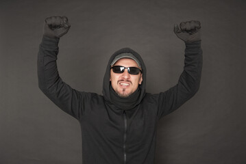 Wall Mural - Screaming Man in the black hoody with hood wearing sunglasses with fist up
