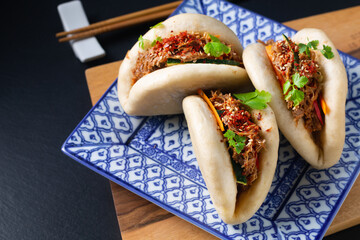 Food concept Homemade organic Pulled Beef Bao Buns or Gua Bao in sqare plate on black background with copy space