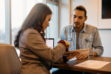 Job candidate and human resource manager using touchpad during meeting in office.