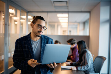 Latin American businessman working on laptop during meeting in office.