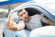 Aggressive Asian male driver showing a middle finger or waving hands to other people while driving a car. Male car driver opened side window and shouting and showing middle finger to camera.