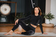 a beautiful woman in black clothes is resting on a yoga mat with a gym