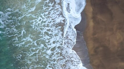 Wall Mural - 4K aerial footage of a golden sandy beach partly submerged by water and covered by snow in Iceland.