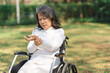 © NanSan - Asian old woman sitting on a wheelchair outdoors in the park Have pain in the arms and wrists