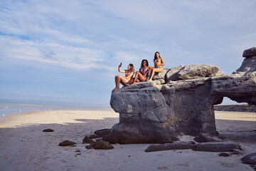 Wall Mural - Friends, beach and selfie for diversity on a rock outdoor for holiday or vacation in summer. Group of women together at sea or ocean for travel in Bali for freedom in nature with water and blue sky