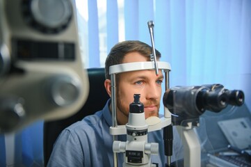 Wall Mural - Handsome young man is checking the eye vision in modern ophthalmology clinic. Patient in ophthalmology clinic