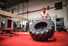 Strong Man Flipping Large Tire At The Gym.
