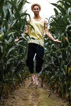 Farm Man In A Hat Jumping And Smiling In A Green Corn Field.