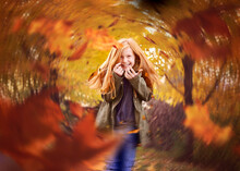 Beautiful Red Haired Girl In Swirling Fall Leaves