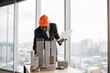 © sofiko14 - Focused african man in black suit and orange hardhat using digital laptop looking at design sustainable 3D megalopolis model on desk at open space office with panoramic windows with blurry cityscape