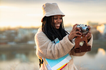 tourist african american woman with camera taking photos of beautiful location, she's happy and exci