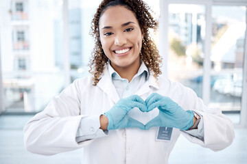 Woman, love and heart hands portrait in hospital for care, trust and support on valentines. Healthcare, dentist and happy black female doctor with hand gesture for affection, romance and kindness.