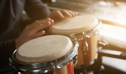 Musician playing hand Bongo Drums indoors closeup. Man with traditional ethnic folk music instrument