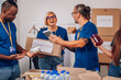 © Zamrznuti tonovi - Diverse volunteers working in a charity donation center and packing clothes and food