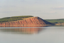 Lake With Clouds In The Sky, Red Hill With Forests On Background. Hill Symmetric Reflection In The Water