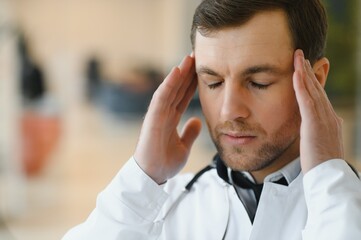 Stressed male doctor. Mid adult male doctor working long hours. Overworked doctor in his office. Not even doctors are exempt from burnout .